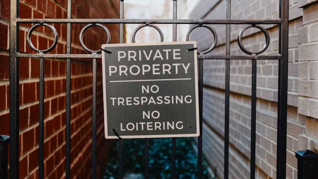 Close-up of no trespassing sign on a gate between townhouses.