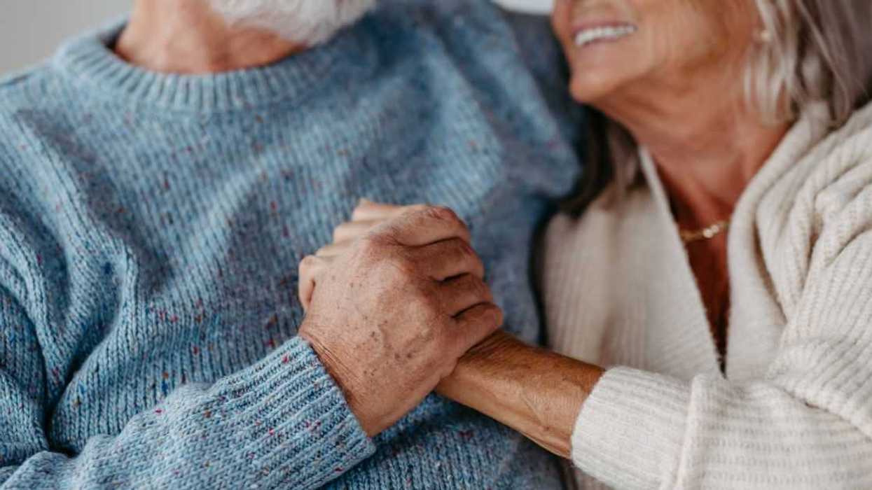 Close-up of senior couple cuddling and holding hands in their home.