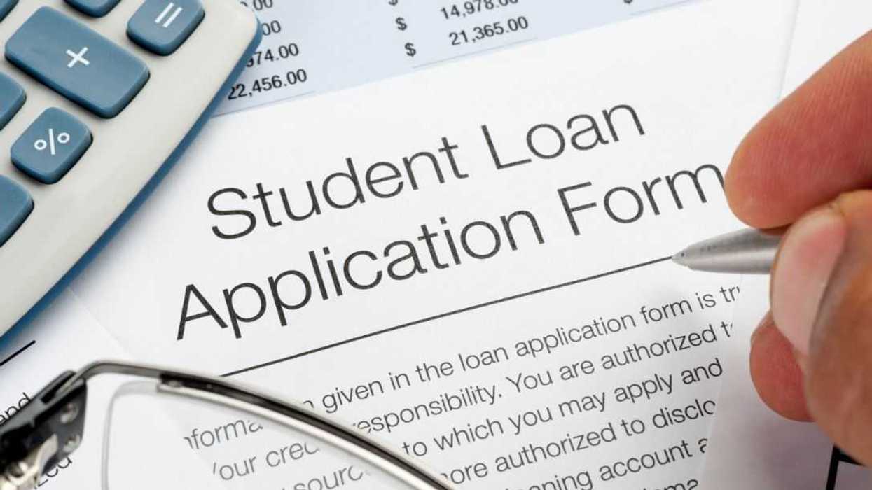 Close up of Student Loan application Form with pen, calculator and writing hand.