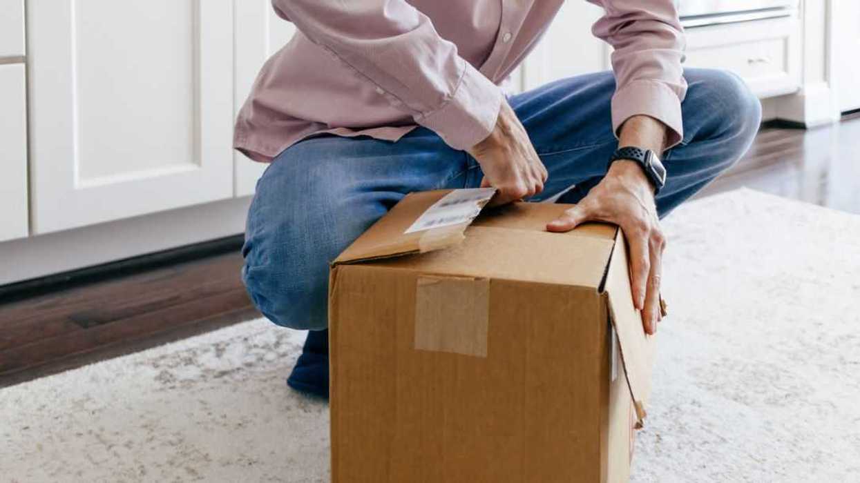 Close-up of unrecognizable man opening package after delivery of online order.