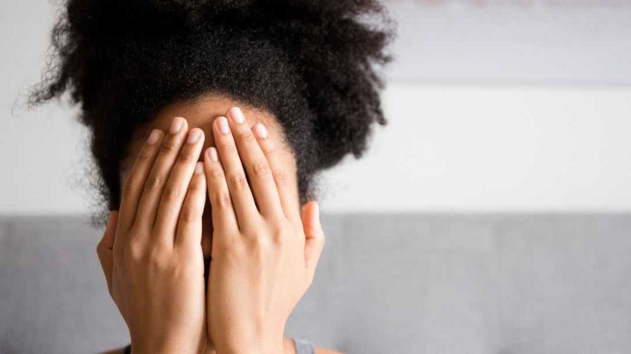 Close-up shot fof a young woman covering face with her hands.