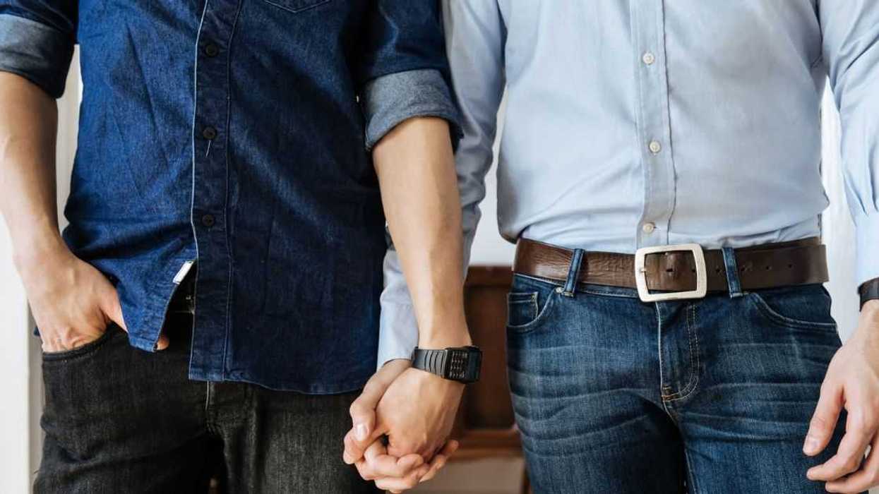 Close up shot of a gay couple holding hands. Focus on their hands.