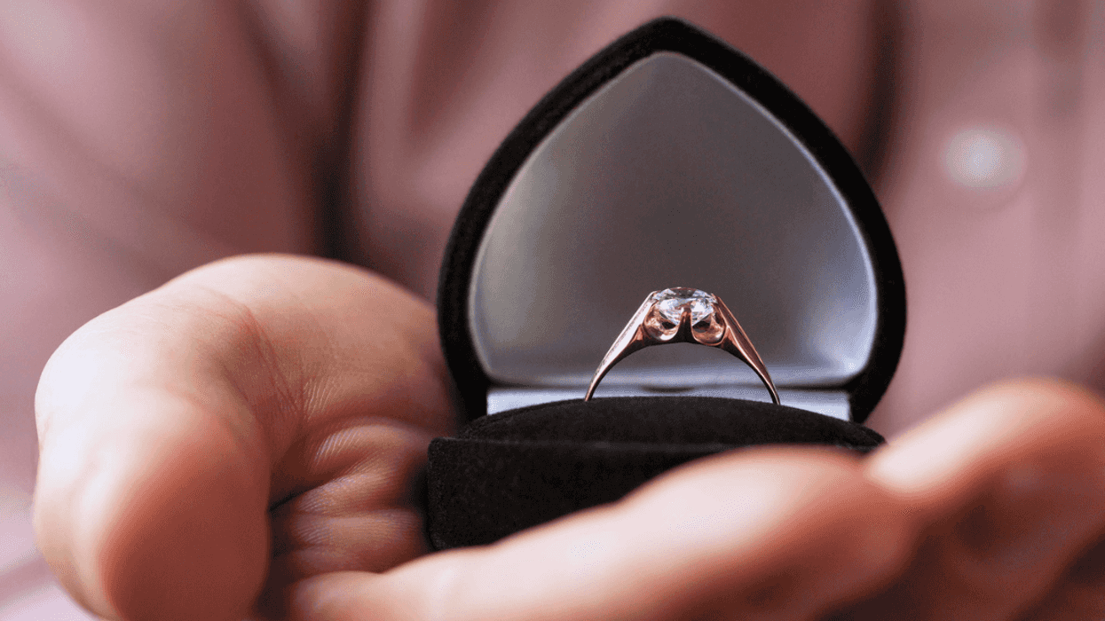 closeup of diamond ring in open heart shaped box in person's hand