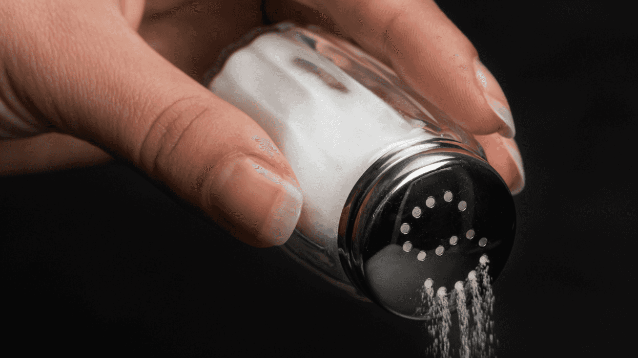 closeup of hand pouring salt from shaker