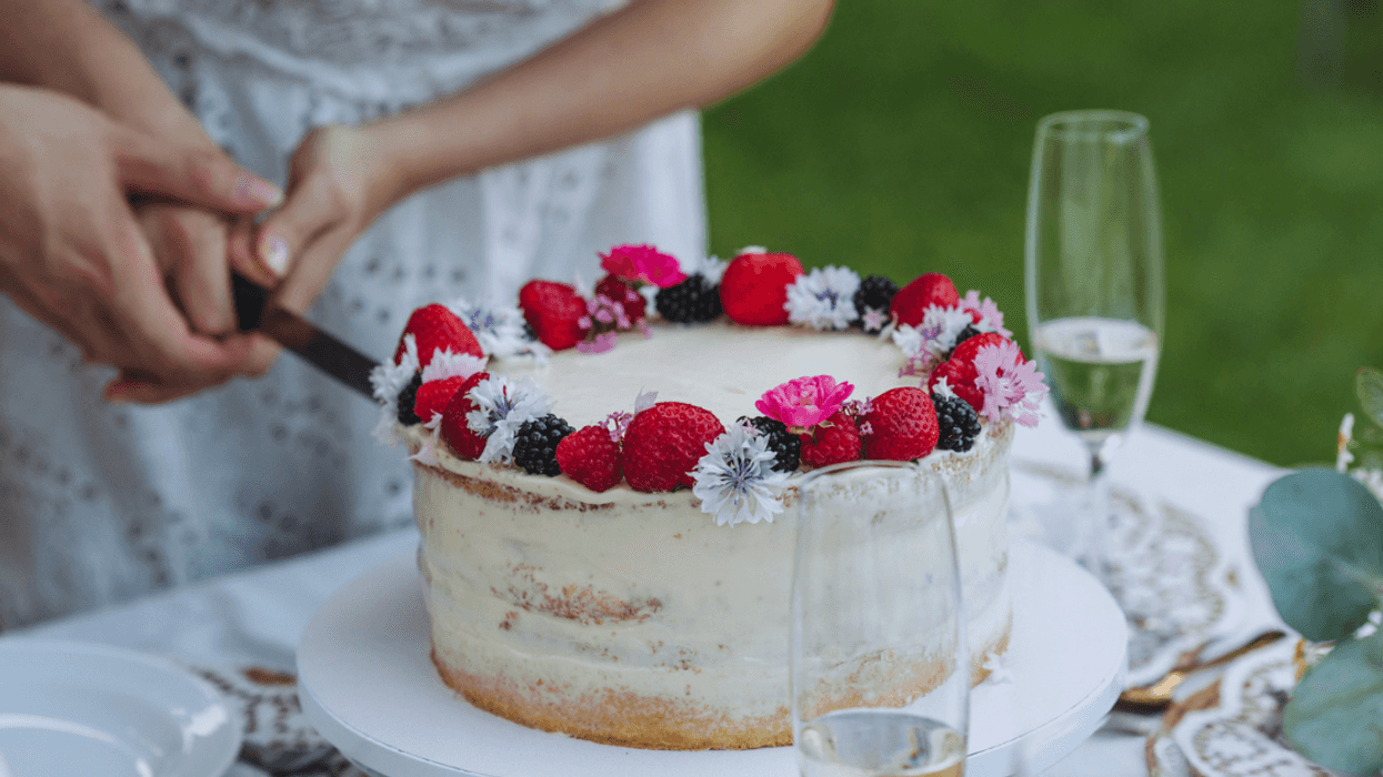 Couple cutting wedding cake with strawberries