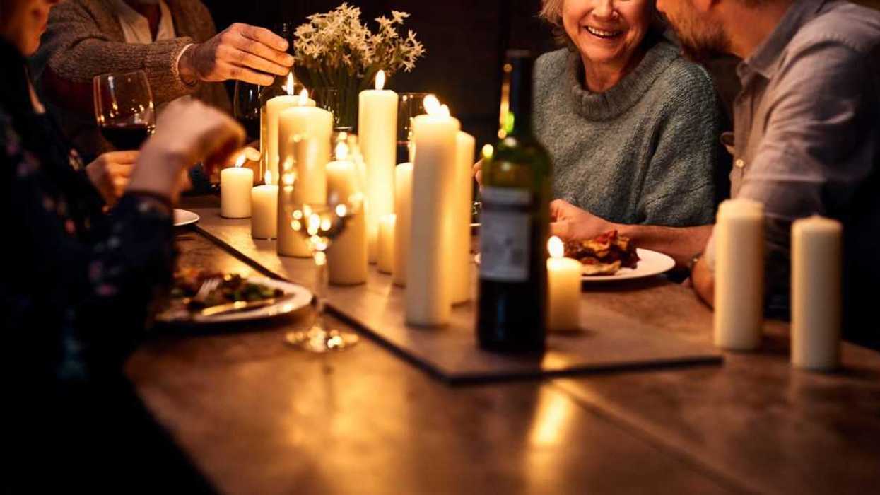 Couple dining with parents in restaurant, with wine and candles on the tables, relaxed dinner party