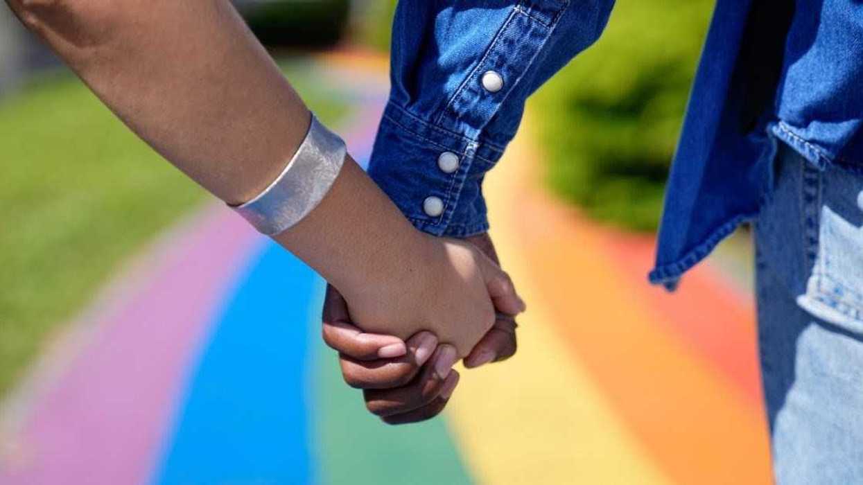 couple holding hands on rainbow walkway