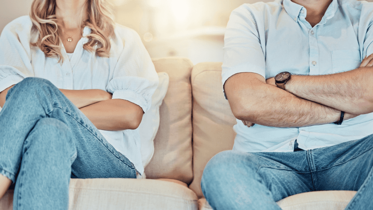 Couple sitting on the sofa with their arms crossed.