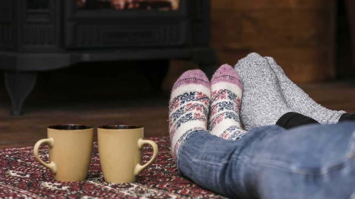 Couples warming feet in front of fireplace.