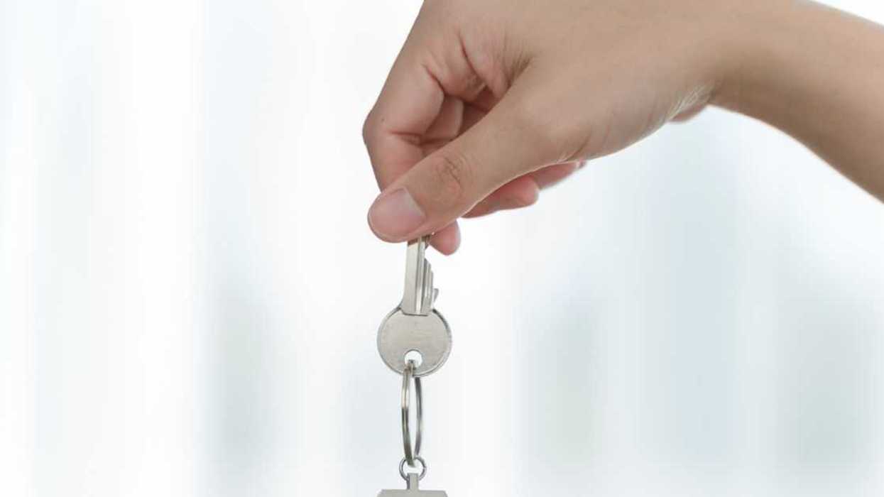 Crop close up of a female hand holding a dangling silver key