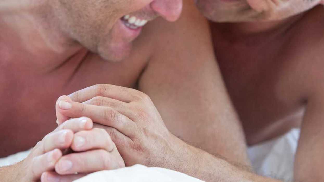 Cropped shot of happy male couple in bed