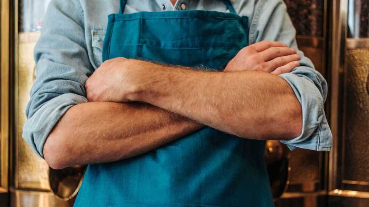 Crossed arms of a coffee roaster in his shop.