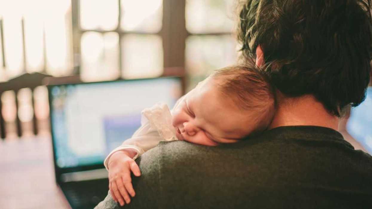 Dad holds sleeping baby over his shoulder