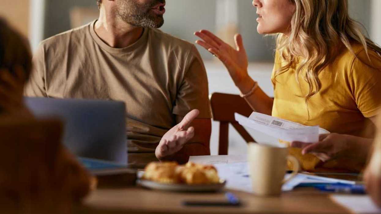 Displeased parents arguing while paying their bills over laptop at home.