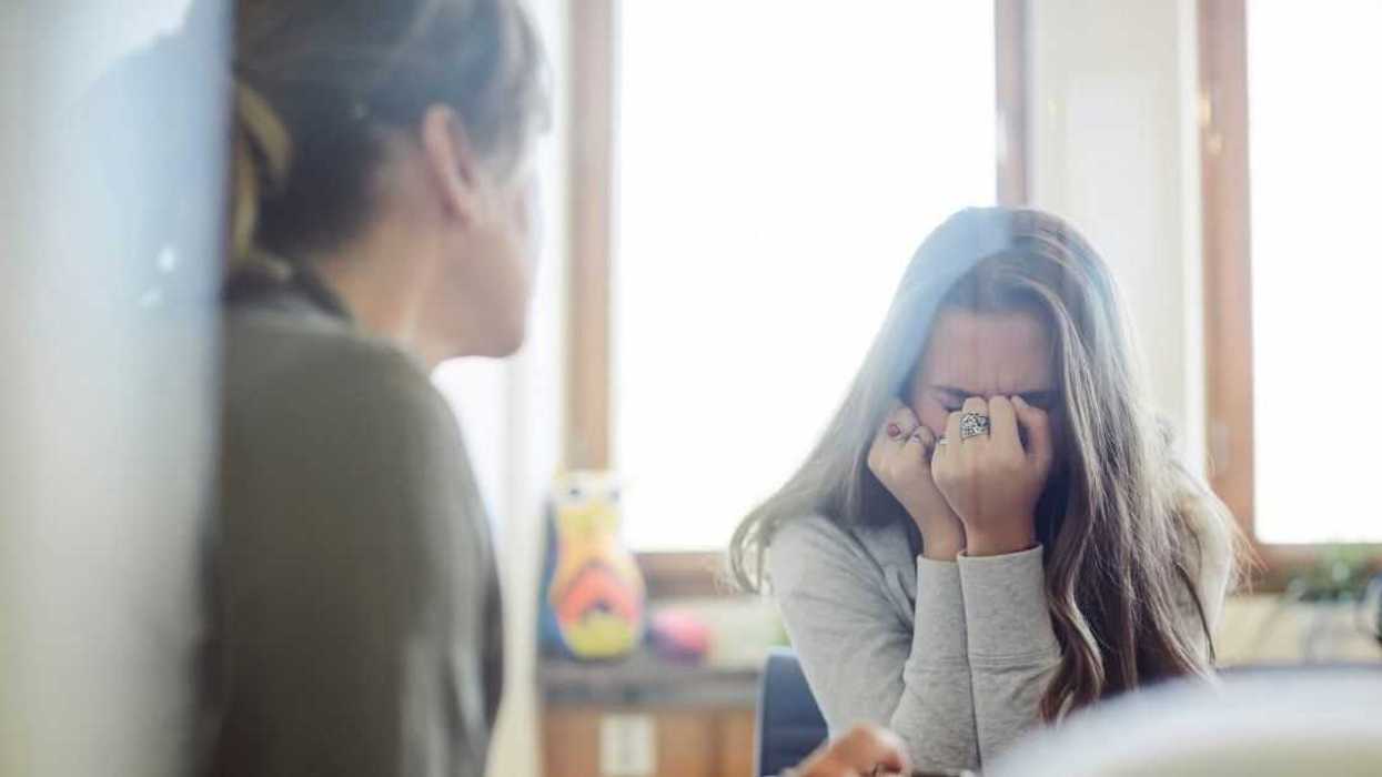 Displeased teenage girl talking to therapist at wellness center.