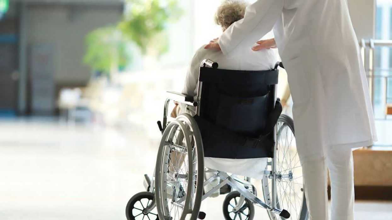Doctor assisting an older, female patient in a wheelchair.