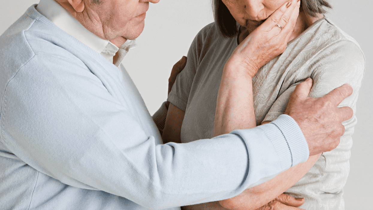 Elderly man caressing elderly woman.