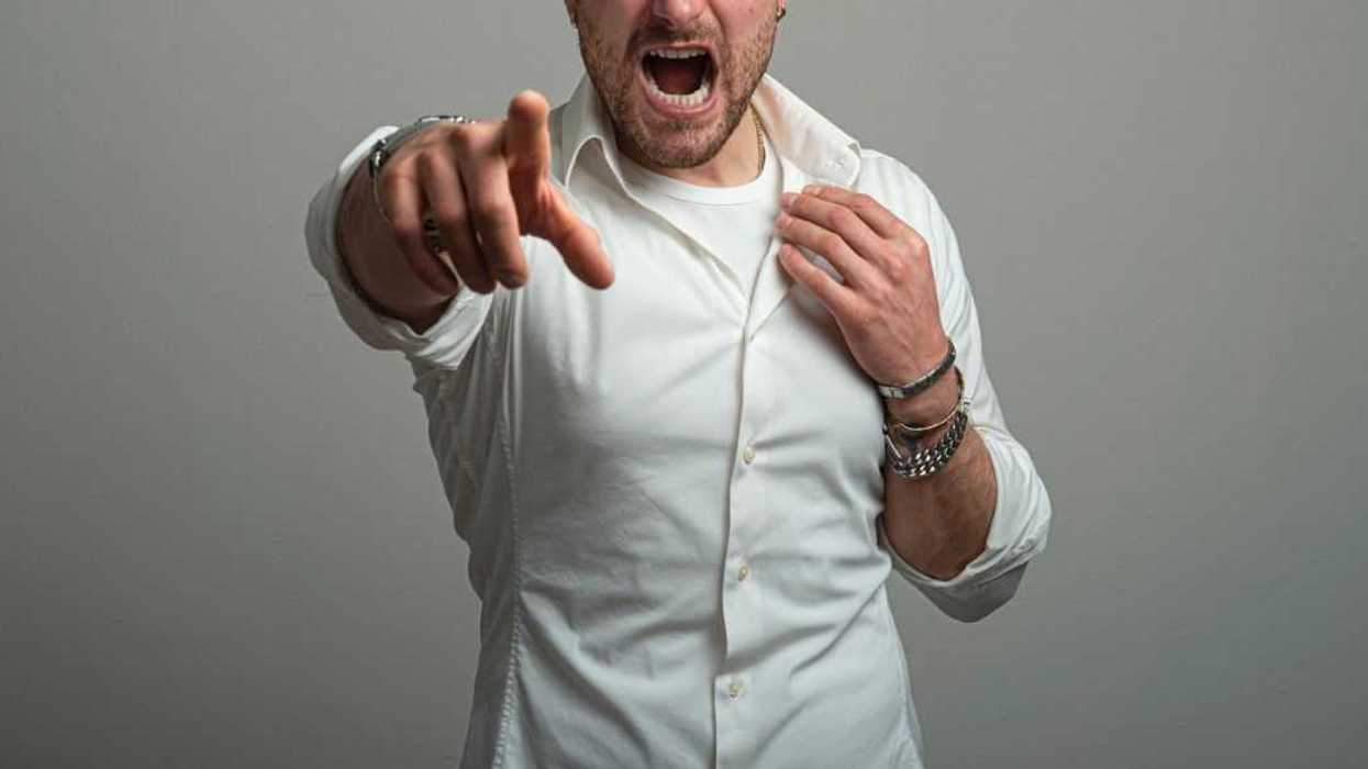 Excited young man screaming while pointing at you.Studio shot.