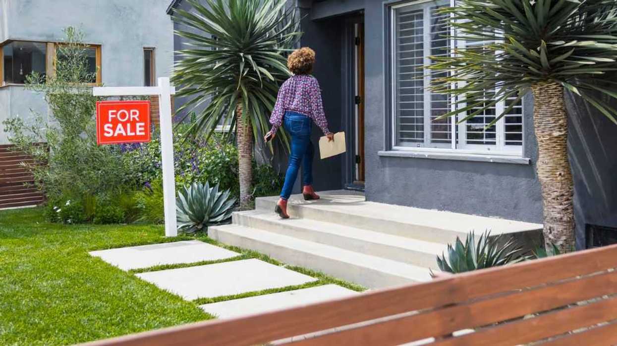 Female real estate agent carrying document while walking into a house.