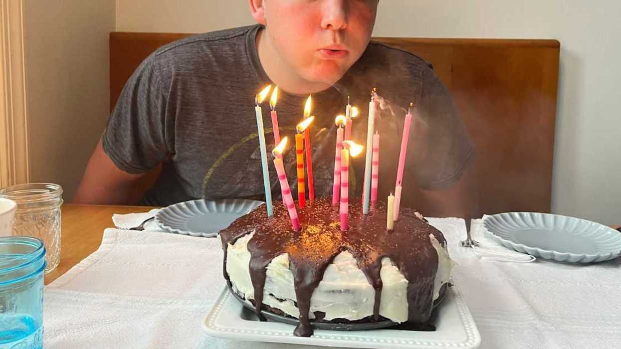 Fifteen-year-old teen boy blowing out his birthday cake candles