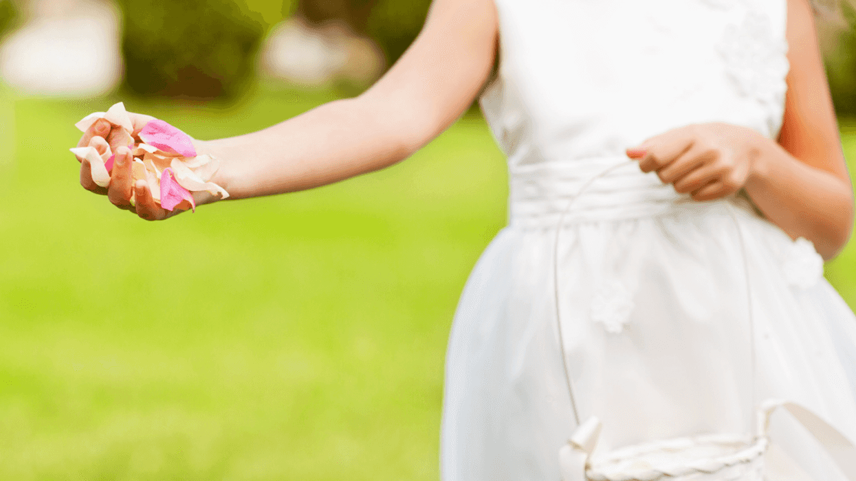 flower girl in white dress with flower petals