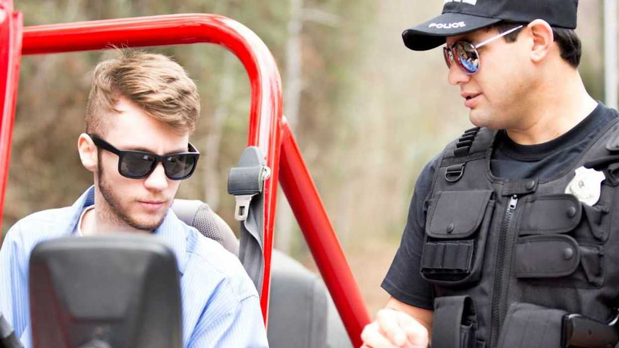 Friendly Latin American police office stops a young man on a rural road. The young man drives an off road vehicle faster than the speed limit and gets a friendly reminder from the policeman.
