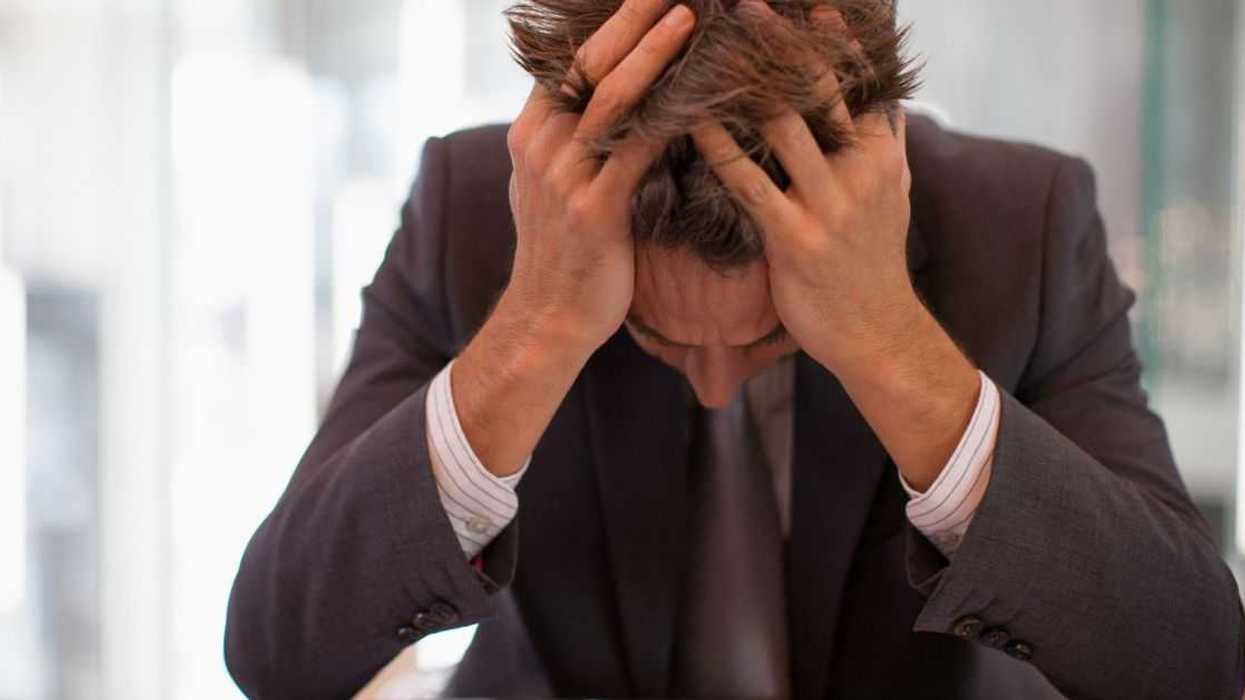 Frustrated businessman sitting at desk with head in hands