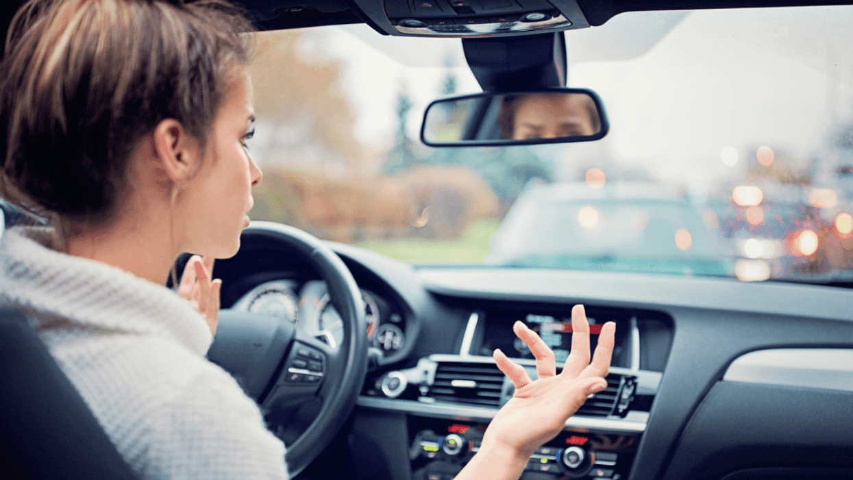 Frustrated young girl in car, is waiting in the traffic jam in a rainy day