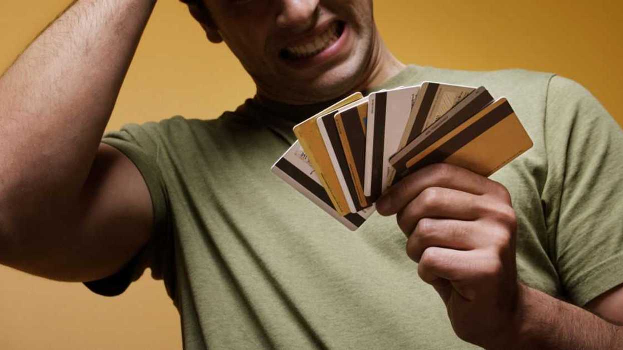 Frustrated young man holding credit cards.