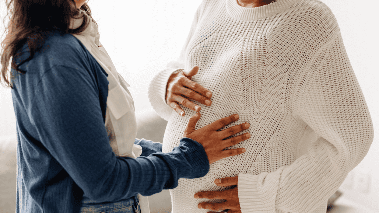 Future mom touching surrogate mother's belly