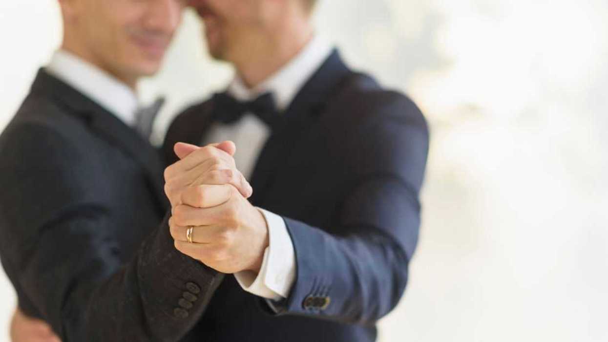 Gay grooms dancing and smiling at a wedding.