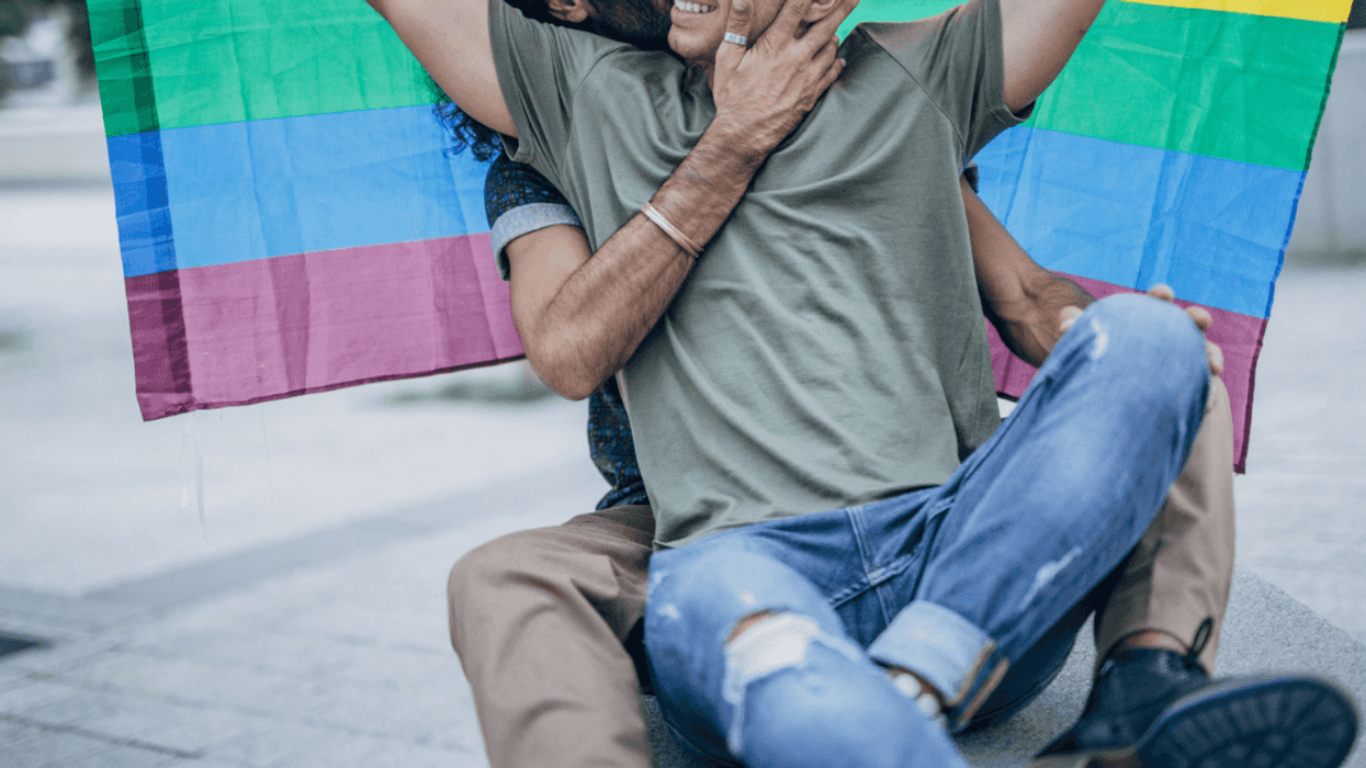 gay male couple under a pride flag
