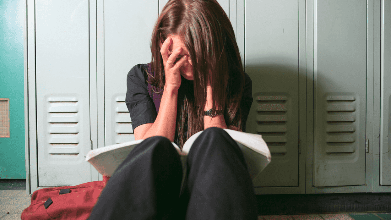 Girl crying against a locker.