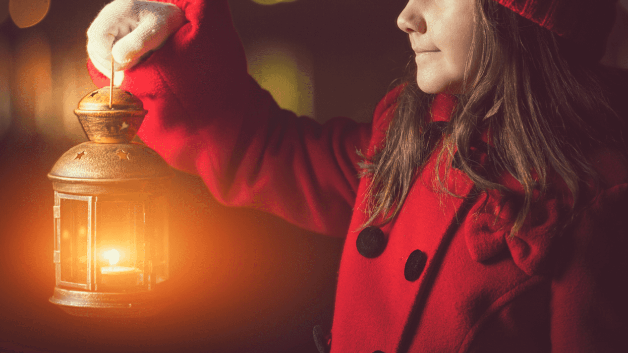 girl in red coat with lantern walking at night