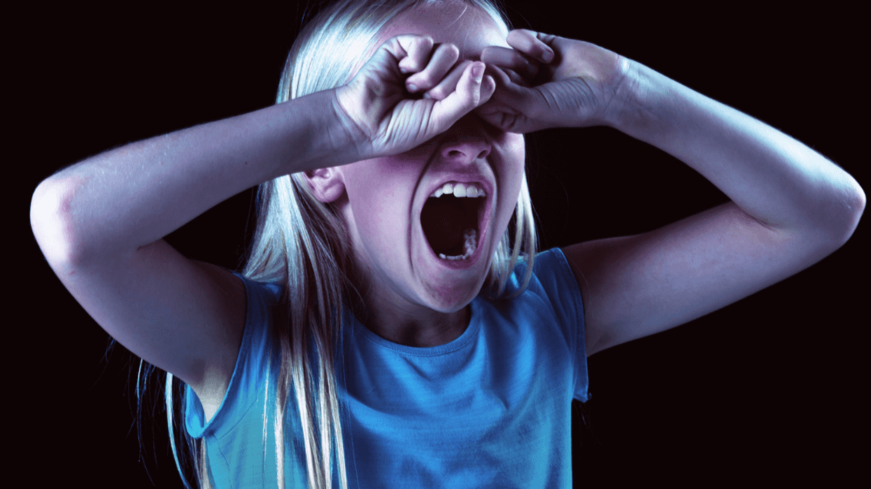 Girl screaming with her eyes covered.