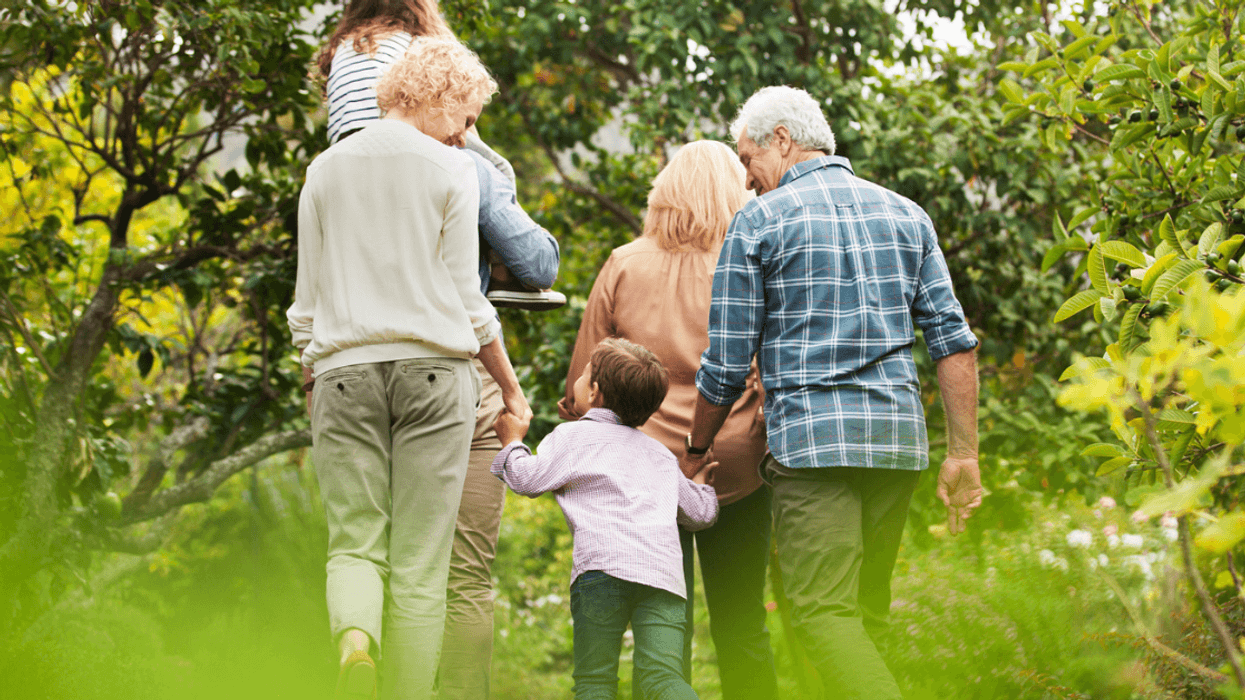 Grandparents walk hand in hand with their grandson on the woods