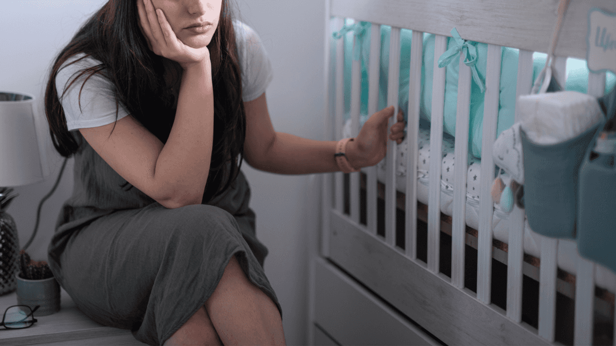 grieving mother seated by empty crib