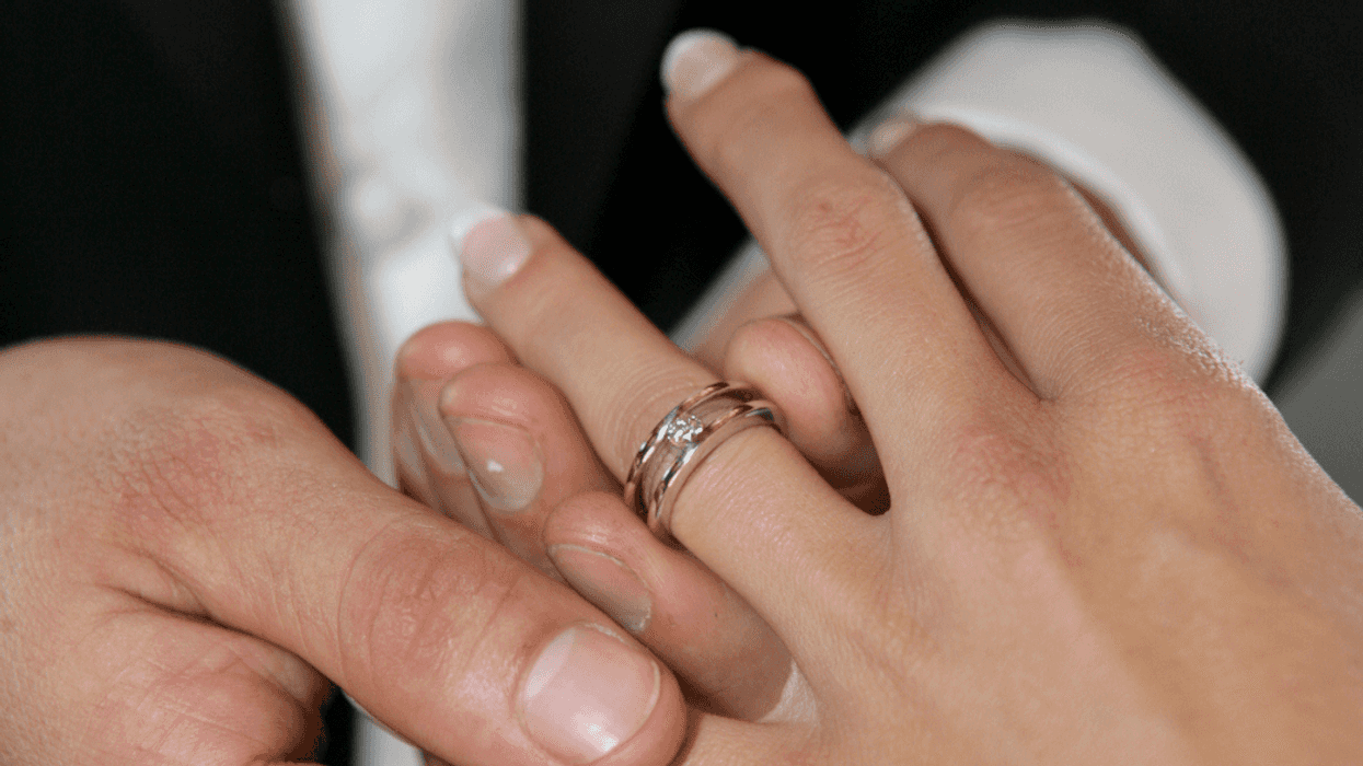 groom putting a ring on bride's finger