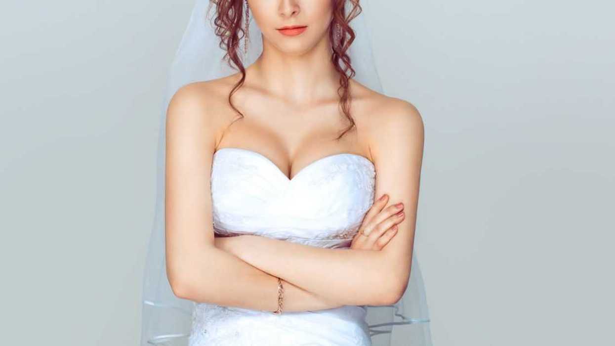Grumpy bride. Sad and disappointed hesitating woman in wedding dress, arms folded, unhappy wife.