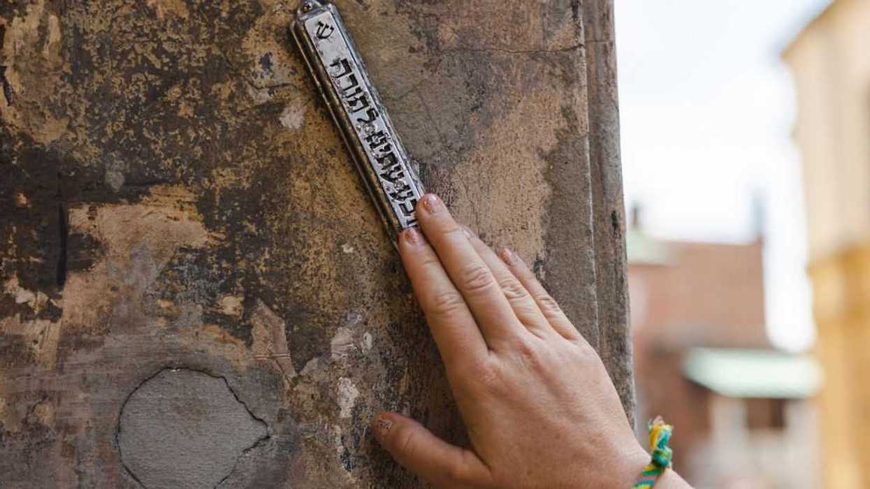 Hand touching mezuzah at the entrance to the house.