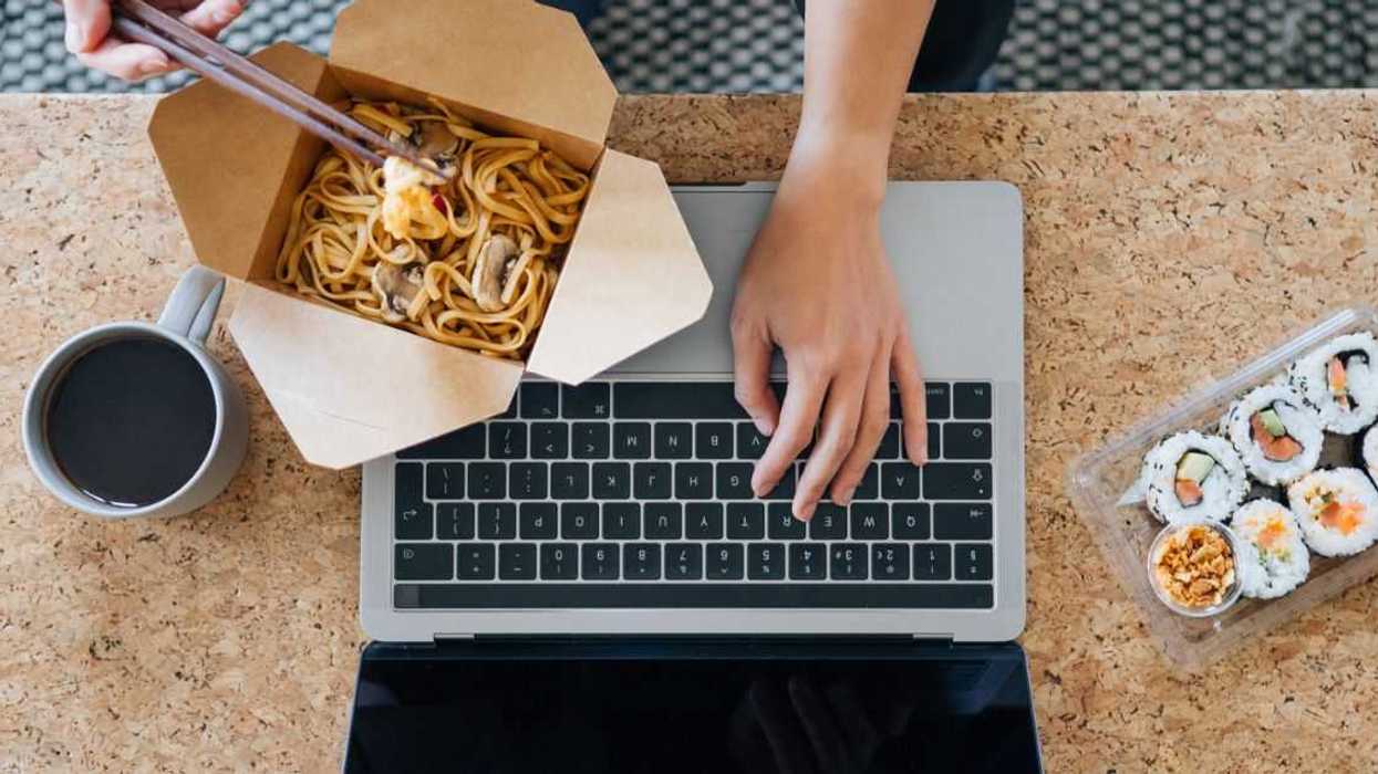 hands at a computer working, while have Chinese for lunch