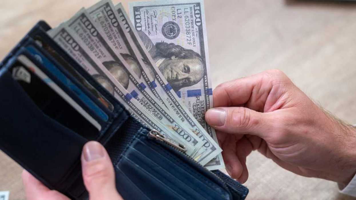 Hands holding a wallet with a small amount of US dollars, close up.