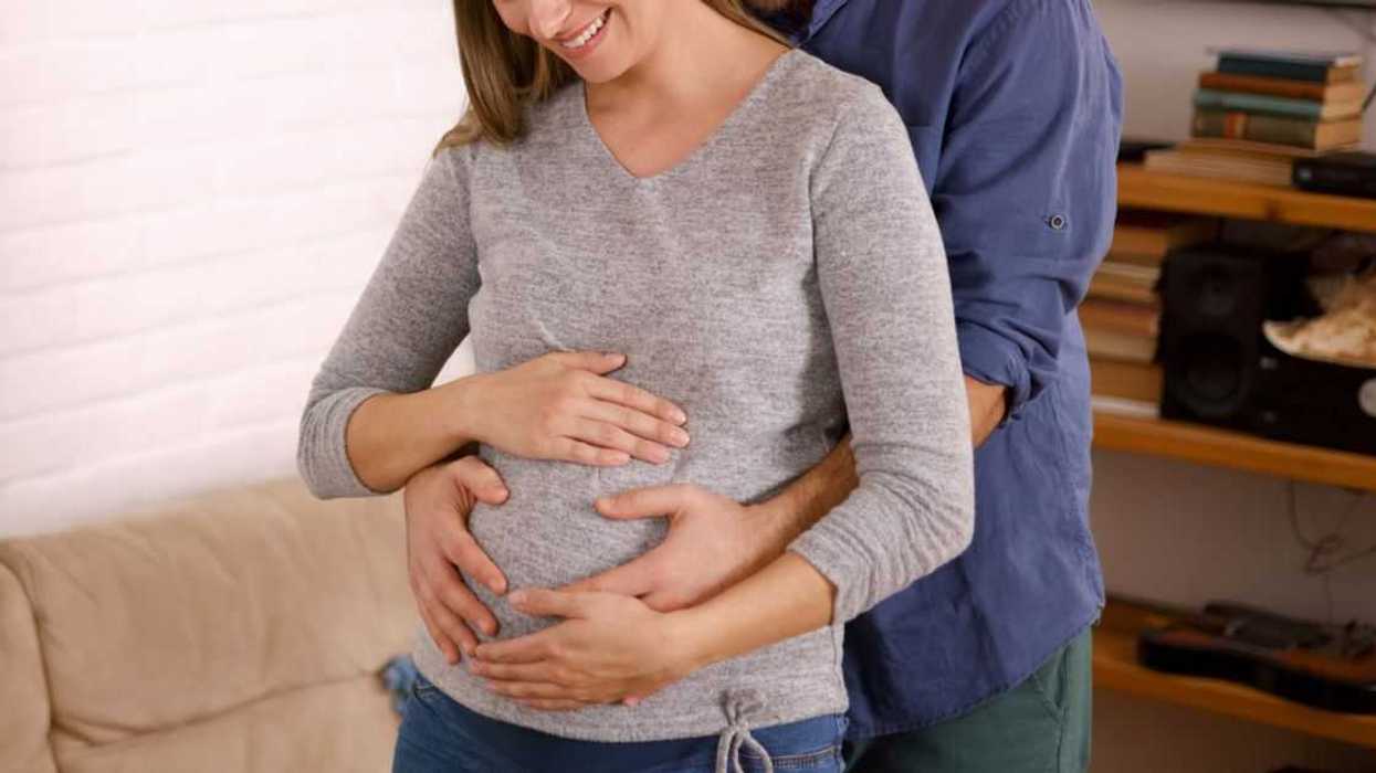 Happy husband caresses the belly of his pregnant wife.