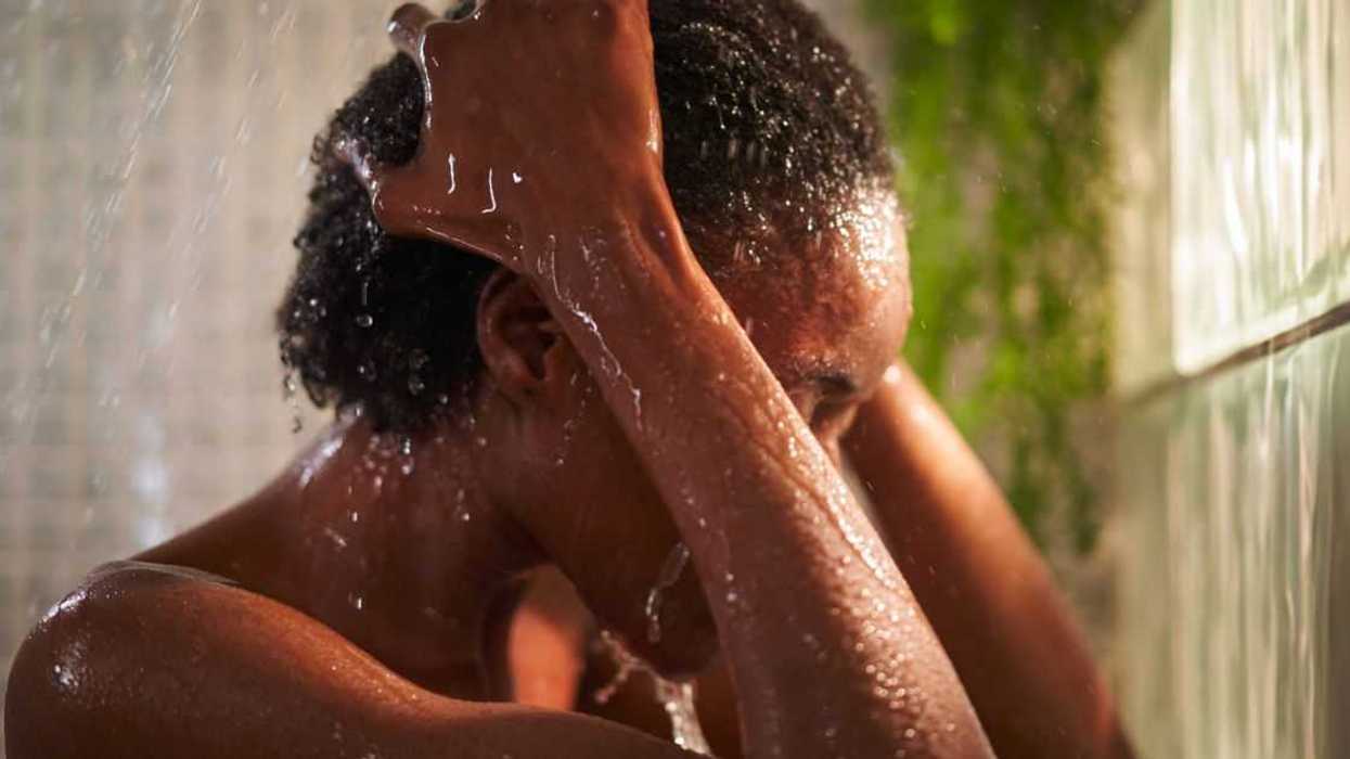 Headshot of an unrecognizable woman taking a shower at home, putting hands on her head, gesturing frustration.