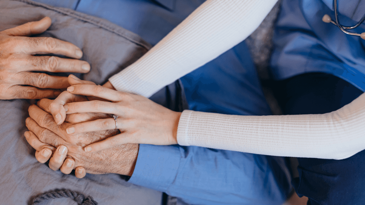 healthcare worker holding older man's hands