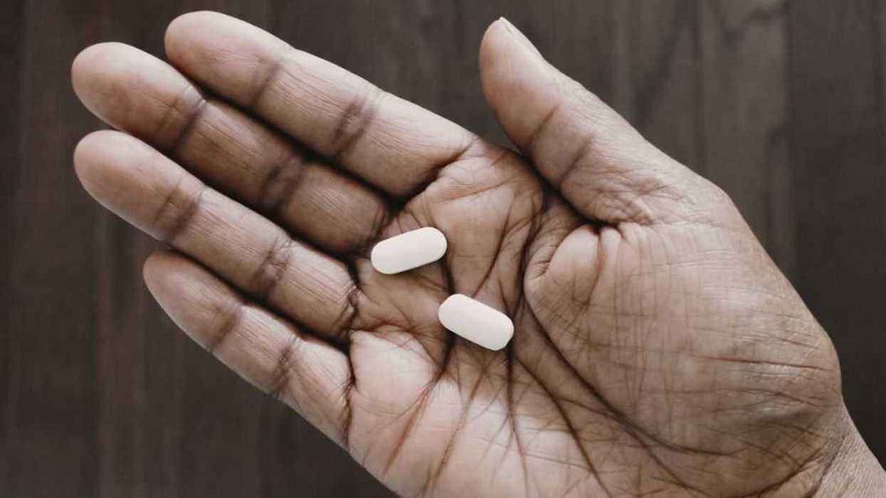 High angle view of unrecognizable woman holding two pills in the palm of her hand.
