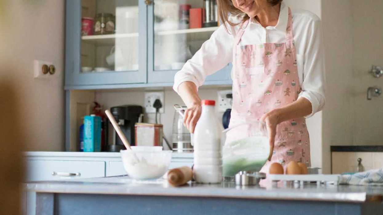 In a kitchen a woman prepares something to bake.