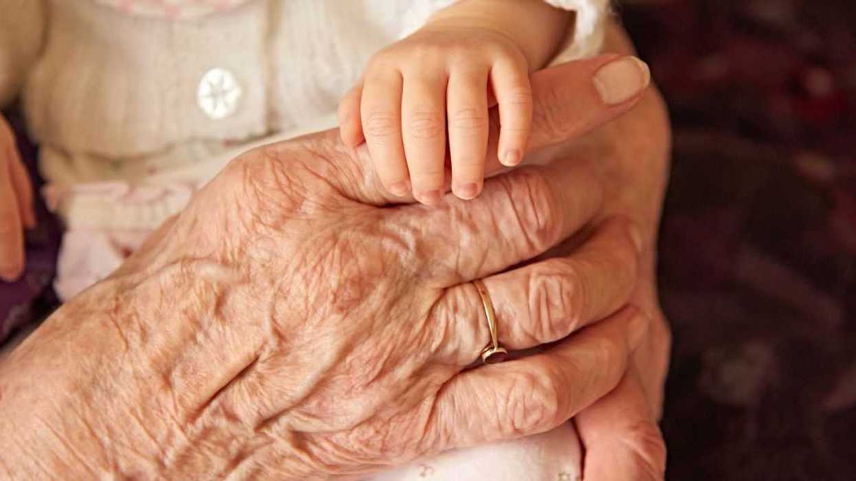 Infant holding an elderly person's hand