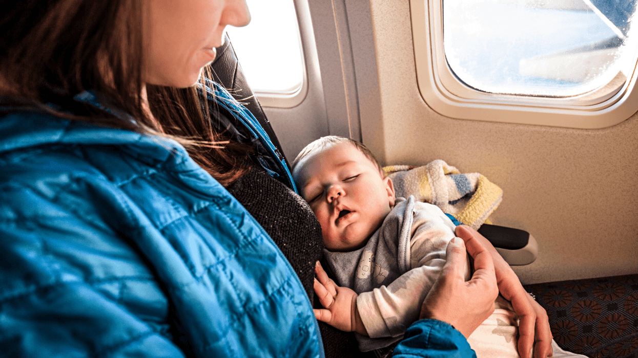 infant sleeping in mother's arms on airplane