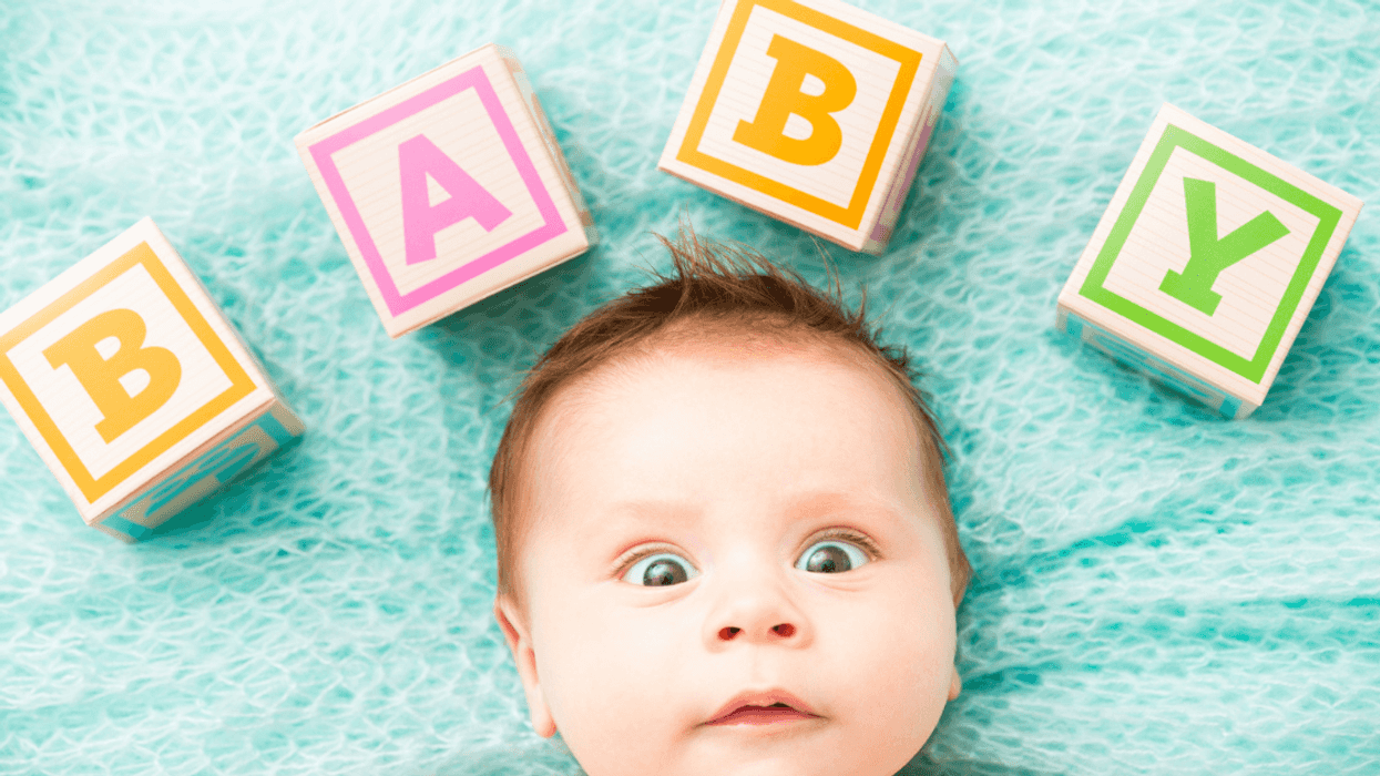 infant with word "BABY" spelled on wooden blocks